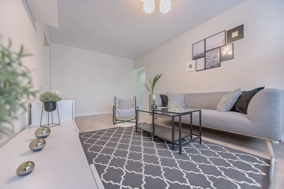 Recouvert d’une housse de drap, avec un canapé, un lampadaire et des cartons emballés dans une pièce lumineuse et spacieuse d’une maison contemporaine neuve